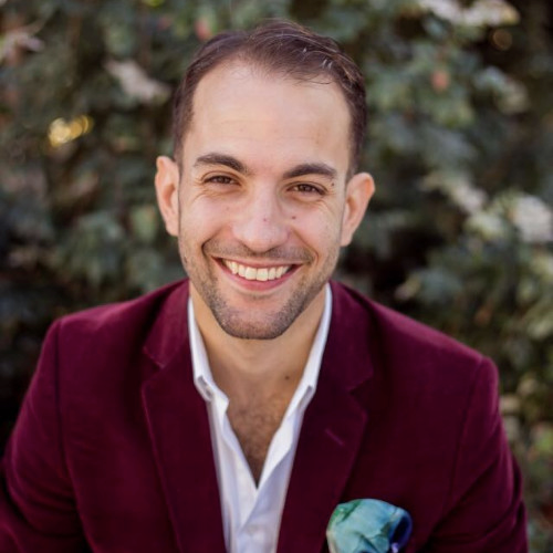 a man in a red jacket smiles at the camera